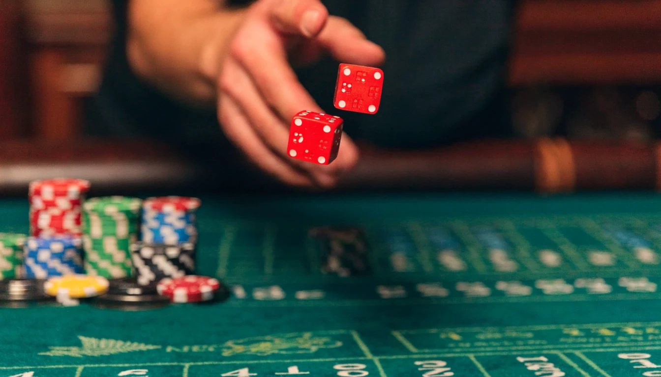 Hand tossing craps dice over a casino table with chips